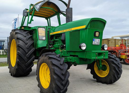 Modernus traktorius dirbamame lauke saulėlydžio metu.